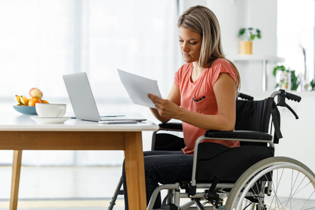Woman in wheelchair reading documents at a table
