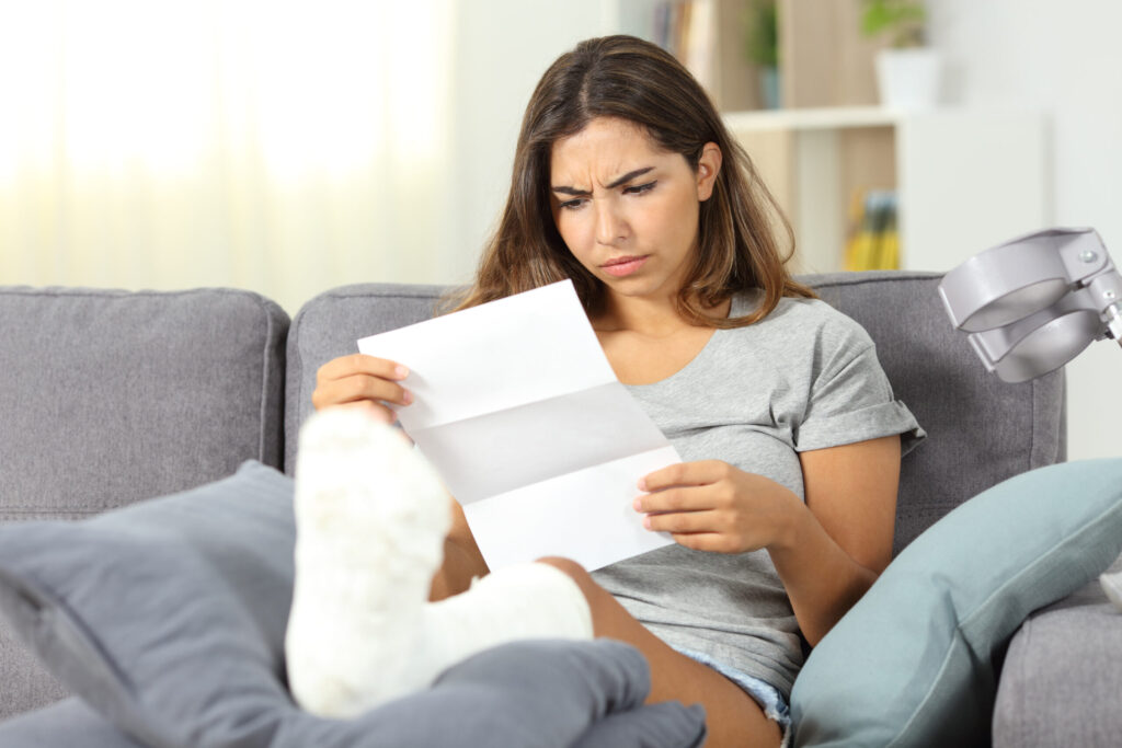 Woman reading a letter while resting her injured foot on a sofa